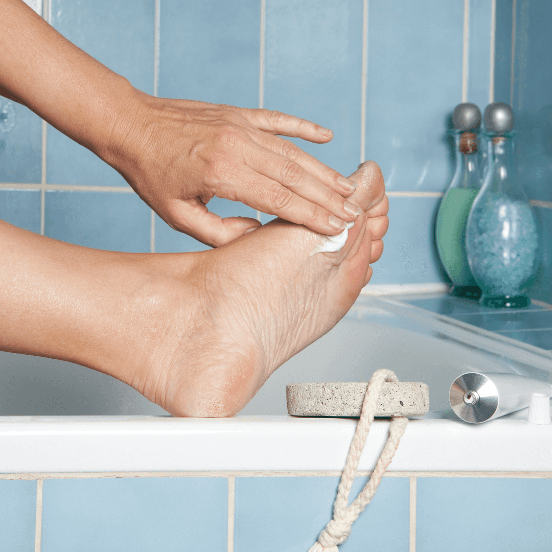 putting on lotion on foot in bathroom